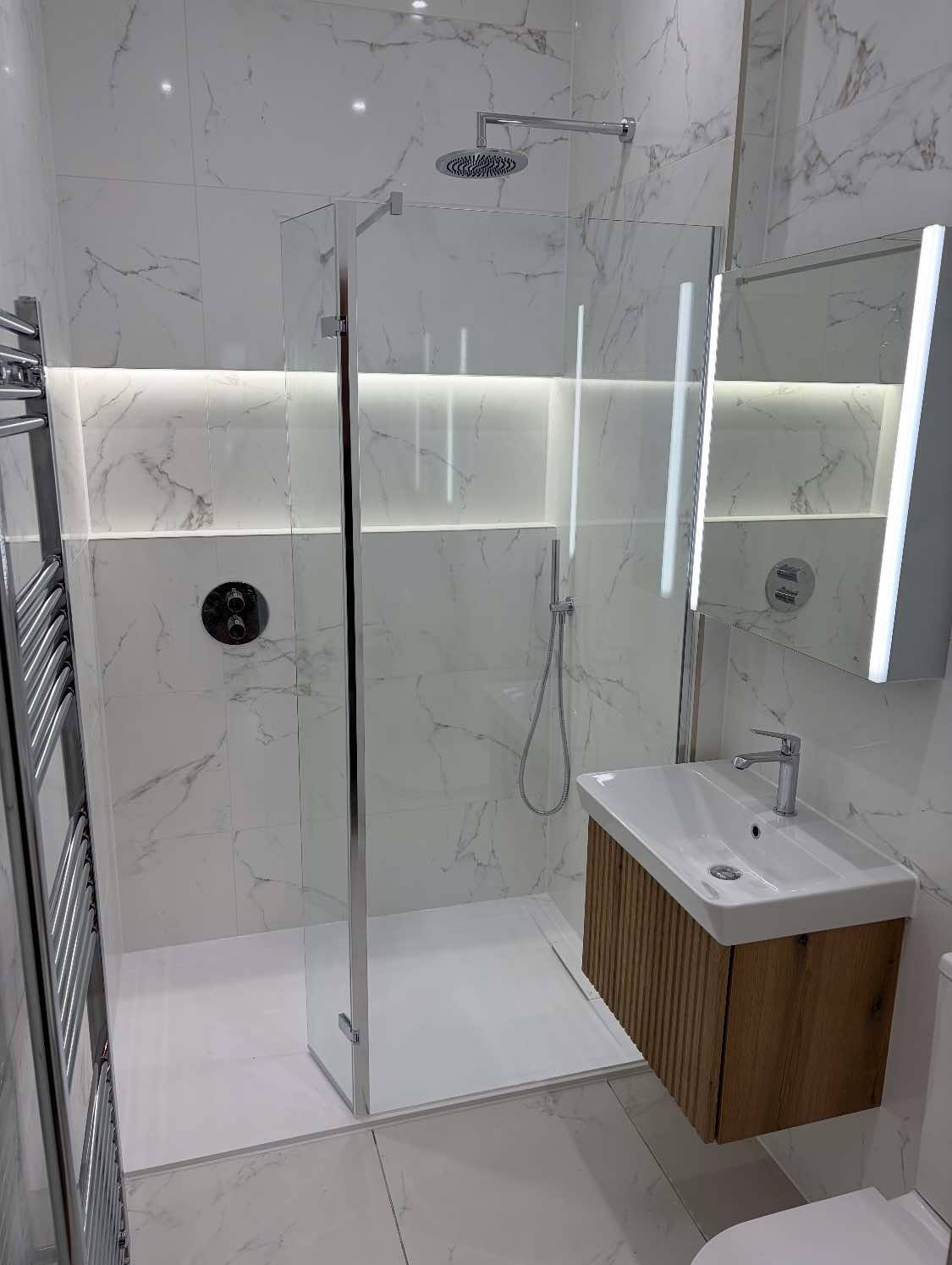 Walk-in shower with marble-effect tiling, illuminated niche and backlit mirror