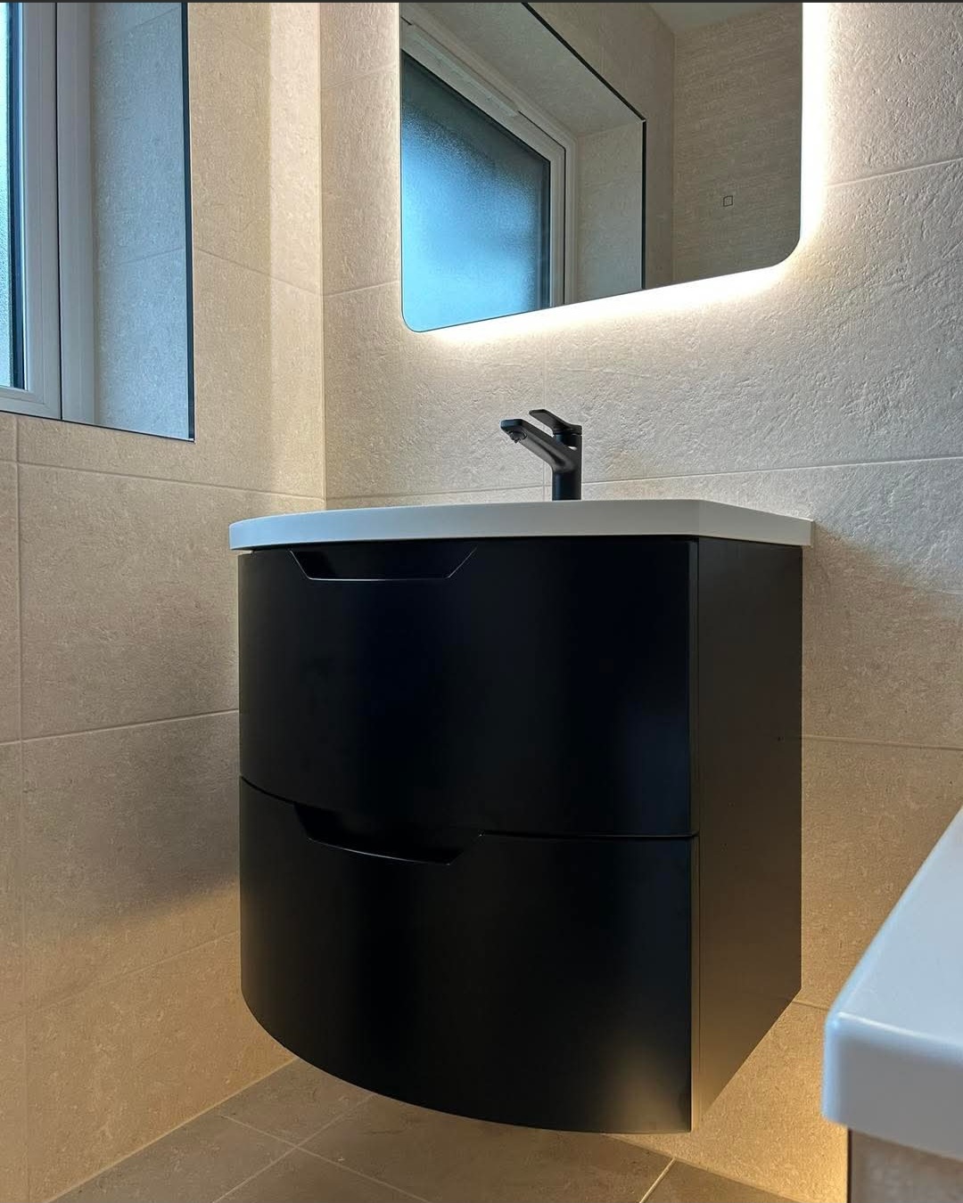 Luxury statement bathroom installation in Fife with sculpted white tiling, freestanding bath and backlit mirror by BDR Bathroom Innovation