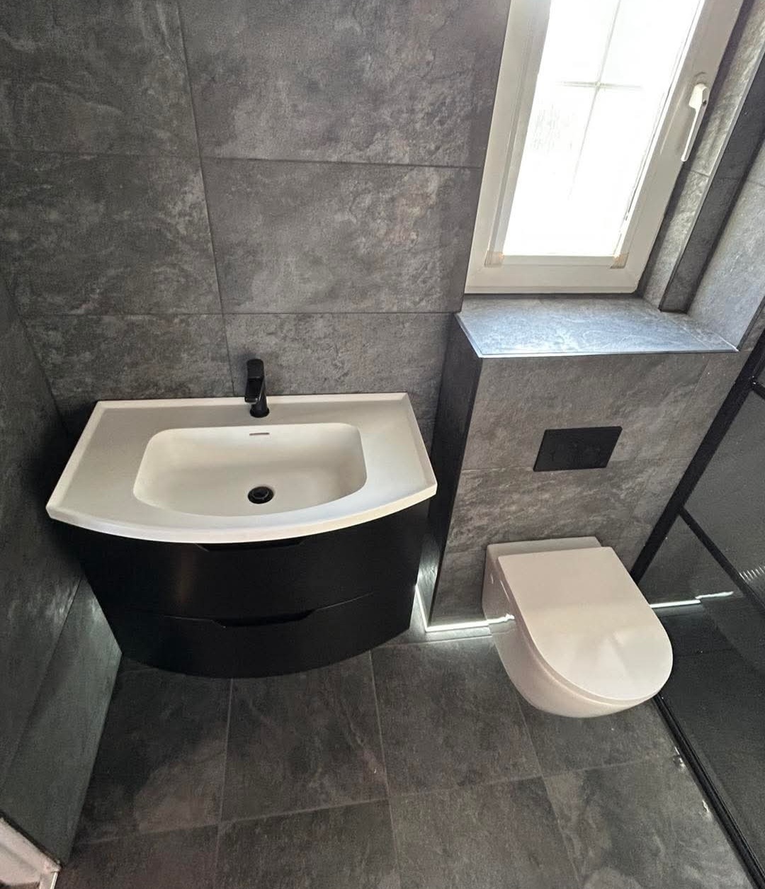 Anthracite tiled wet room corner with heated towel radiator, a completed installation in Fife