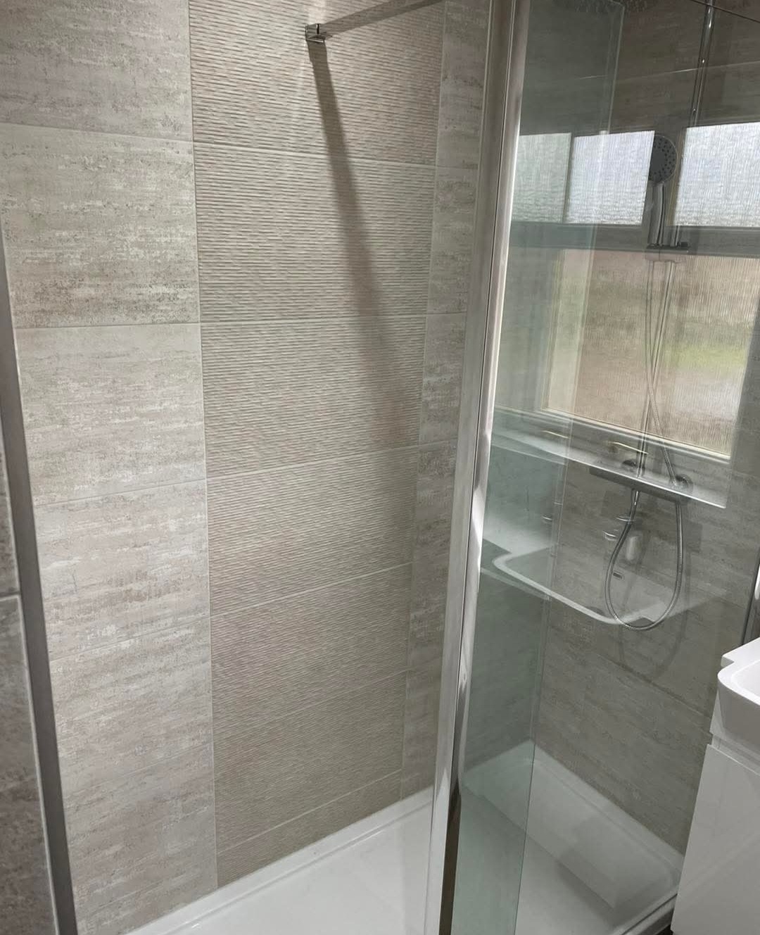 Black rainfall shower head in a dark tiled wet room with lit niche, fitted by wet room installers in Kirkcaldy
